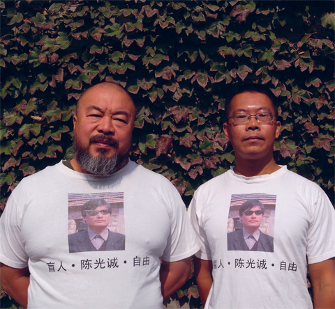 L'avocat défenseur des droits humains Teng Biao et l'artiste Ai Weiwei portent des tee-shirts « Libérez Chen Guangcheng » (Chine, octobre 2011). Chen Guangcheng, conseiller juridique autodidacte et prisonnier d'opinion, est illégalement assigné à résidence depuis qu'il a été libéré de prison, en septembre 2010. © DR