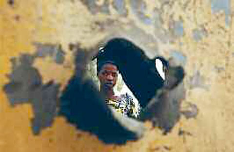 Une femme à travers un impact sur la tôle d'un véhicule ayant sans doute appartenu à des rebelles islamistes et détruit lors de frappes aériennes françaises au Mali, dans la ville de Diabali, récemment libérée (24 janvier 2013).
