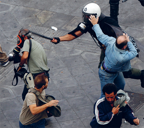Un policier anti-émeute frappe Panagiotis Tzamaros, reporter photographe, lors d'une manifestation sur la place Syntagma à Athènes, en Grèce (5 octobre 2011). © REUTERS/Yannis Behrakis