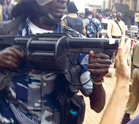 Un policier braque son arme sur le photojournaliste Marc Hofer lors de manifestations à Kampala, en Ouganda (mai 2011). Yoweri Museveni, président de l'Ouganda, a traité les journalistes d' « ennemis » parce qu'ils avaient fait connaître un type de protestation consistant à se rendre à pied à son travail pour protester contre la hausse des prix. © AP Photo