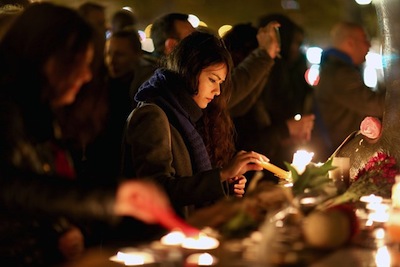 Une jeune femme allume une bougie en hommage aux victimes des attaques du 13 novembre à Paris.