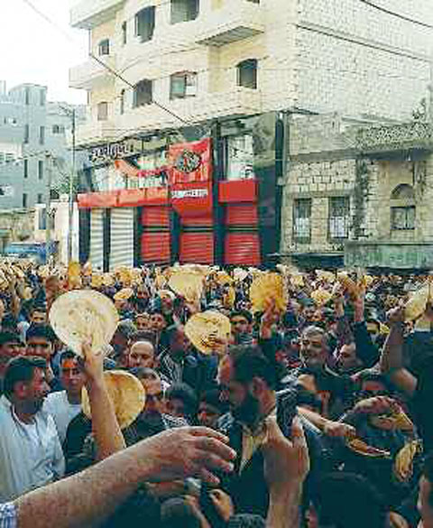 Des manifestants de Baniyas brandissent des galettes de pain et scandent des slogans pour témoigner leur solidarité envers ceux de Deraa (3 mai 2011). © REUTERS/Handout