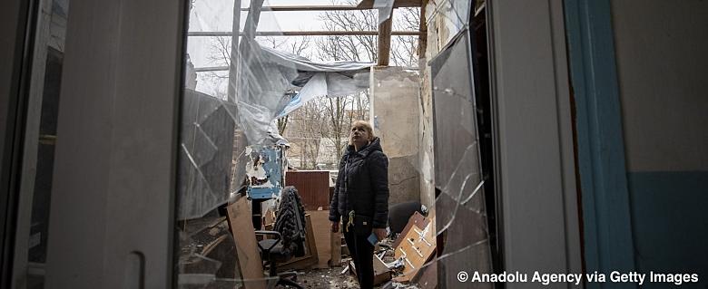Une femme voit un bâtiment endommagé par la guerre entre la Russie et l'Ukraine à Orikhiv, en Ukraine, le 28 février 2023.