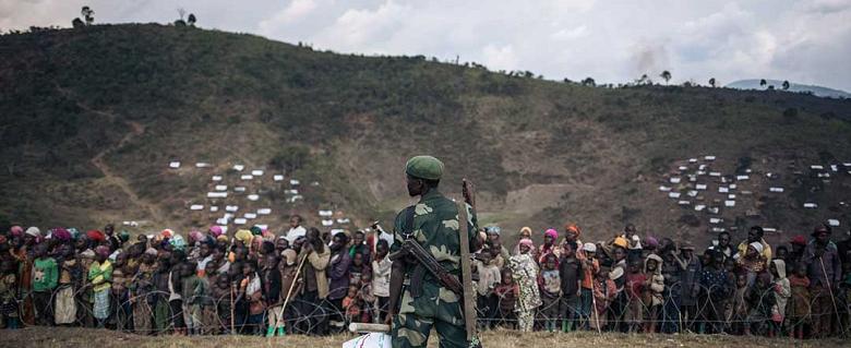 Soldat congolais devant des déplacés dans le camps de Bijombo, Sud Kivu
