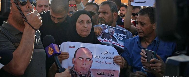 manifestants dont une femme qui tient une affiche de protestation pour Nizar Banat